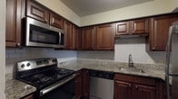 Located at 360 Broad Meadows Blvd in Columbus, Ohio, this single-floor residence offers a functional and cohesive layout designed for comfortable everyday living. Dark hardwood-style flooring flows consistently throughout the living areas and bedrooms, providing a warm, unified aesthetic against the neutral, light-toned walls.

The kitchen is a standout feature, equipped with rich, dark wood cabinetry that extends to the upper walls for generous storage. Granite countertops add a refined touch, complemented by a classic white subway tile backsplash. Stainless steel appliances — including a range, over-the-range microwave, dishwasher, and refrigerator — complete the well-outfitted space. A pass-through window connects the kitchen to the living area, enhancing the open feel of the floor plan.

The living room is spacious and airy, featuring a ceiling fan with light fixture and a pass-through view into the kitchen. Natural light enters through windows fitted with blinds, offering outdoor views of surrounding trees.

The bedrooms are well-proportioned, each featuring the same dark hardwood-style floors, neutral walls, and windows that allow in natural light. Textured ceilings are present throughout several rooms.

The bathroom is clean and modern, featuring gray tile flooring and wainscoting, a white tub-shower combination, and a dark wood vanity with a white sink — offering a crisp, contemporary finish.