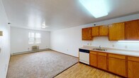 This single-floor unit offers a practical and well-organized layout designed for comfortable everyday living. The open-concept main area seamlessly connects the living space and kitchen, with light wood-style flooring in the kitchen zone transitioning to neutral carpet in the living area. The kitchen is equipped with warm oak-toned cabinetry providing ample upper and lower storage, a built-in dishwasher, an electric range, a refrigerator, and a single-basin sink. A skylight-style ceiling fixture brightens the kitchen, while a window allows natural light into the living area. A wall-mounted HVAC unit and baseboard heating ensure year-round climate control.

The bedroom is a well-sized, carpeted retreat featuring a window with outdoor views, baseboard heating, and direct access to a closet with built-in shelving. An accessible bathroom is thoughtfully designed with grab bars, a wall-mounted sink, a medicine cabinet, and wood-style flooring, making it suitable for a range of mobility needs. The entryway connects the living area to the front door via a short, open corridor with wood-style flooring, completing the efficient and functional flow of this single-level unit.
