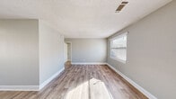 Located at 172 Fox Trace in Augusta, Georgia, this single-story, 2-bedroom, 1-bathroom home offers a practical and efficient layout. The interior is finished with a consistent neutral gray palette and white trim throughout, creating a clean, cohesive aesthetic. Durable wood-look luxury vinyl plank flooring runs through the living areas and primary bedroom, while the secondary bedrooms feature plush carpeting for added comfort.

The living room is bright and open, benefiting from multiple windows that allow natural light to fill the space. A front entry door with a window panel further enhances the welcoming atmosphere. The kitchen is well-equipped with white upper cabinetry, a stainless steel refrigerator, an electric range, and a built-in sink, with a secondary door providing convenient exterior access. A textured ceiling treatment is visible throughout the common areas.

Both bedrooms are well-lit, each featuring windows with blinds that offer outdoor views and natural light. The primary bedroom includes wood-look flooring and access to the hallway, while the secondary bedroom is carpeted and benefits from a dual-window corner layout. The bathroom is functional and clean, featuring a tiled shower-tub combo, a toilet, and a window that brings in natural light and ventilation.