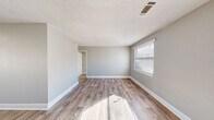Located at 172 Fox Trace in Augusta, Georgia, this single-story, 2-bedroom, 1-bathroom home offers a practical and efficient layout. The interior is finished with a consistent neutral gray palette and white trim throughout, creating a clean, cohesive aesthetic. Durable wood-look luxury vinyl plank flooring runs through the living areas and primary bedroom, while the secondary bedrooms feature plush carpeting for added comfort.

The living room is bright and open, benefiting from multiple windows that allow natural light to fill the space. A front entry door with a window panel further enhances the welcoming atmosphere. The kitchen is well-equipped with white upper cabinetry, a stainless steel refrigerator, an electric range, and a built-in sink, with a secondary door providing convenient exterior access. A textured ceiling treatment is visible throughout the common areas.

Both bedrooms are well-lit, each featuring windows with blinds that offer outdoor views and natural light. The primary bedroom includes wood-look flooring and access to the hallway, while the secondary bedroom is carpeted and benefits from a dual-window corner layout. The bathroom is functional and clean, featuring a tiled shower-tub combo, a toilet, and a window that brings in natural light and ventilation.
