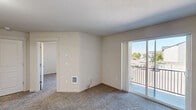 Located in Post Falls, Idaho, this one-bedroom, one-bathroom apartment offers a functional and well-designed single-floor layout. The open living room features plush carpeting and a wall-mounted HVAC unit, and flows directly onto a private balcony through a sliding glass door, providing natural light and outdoor views of the surrounding area. The entryway features durable wood-look flooring that transitions seamlessly into the main living spaces.

The galley-style kitchen is a standout feature, offering rich dark-wood cabinetry with modern hardware, light-toned countertops with generous workspace, and black appliances including a refrigerator, range, and built-in microwave. A double sink and ample cabinet storage add to the kitchen's practicality, while wood-look flooring completes the clean, cohesive look.

The bedroom is a comfortable, carpeted retreat with a ceiling fan, a natural light-filled window with vertical blinds, and a closet for storage. The full bathroom includes a combination tub and shower with a white surround, providing a clean and straightforward design. Throughout the unit, neutral wall tones and consistent finishes create a cohesive, move-in-ready atmosphere suited for comfortable everyday living.
