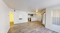This single-floor residence offers a well-organized, functional layout designed for comfortable everyday living. The open-concept living area is anchored by durable wood-look flooring and features a ceiling fan, a built-in wall heater, and direct sightlines into the kitchen, creating a bright and cohesive communal space. A sliding glass door allows natural light to fill the room and provides outdoor access.

The kitchen is thoughtfully designed with gray cabinetry, laminate countertops, white appliances including a range and refrigerator, a double stainless steel sink, a dishwasher, and an overhead light fixture. A peninsula-style counter connects the kitchen to the living area, offering additional workspace and a natural divider between the two zones.

The bedrooms are carpeted for comfort and feature windows with vertical blinds that admit natural light. The primary bedroom is generously proportioned, while the secondary bedroom offers a quieter, equally well-lit retreat.

Both bathrooms are finished consistently, each featuring a single-sink vanity with gray cabinetry, a tub-shower combination with white tile surround, wood-look flooring, and a large mirror. A dedicated laundry room houses a washer and dryer, a utility shelf above, and additional countertop space, adding practical convenience to the home's overall layout.