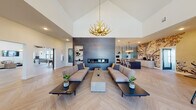 The Star Crest Ranch clubhouse at 680 S Calhoun Pl in Star, Idaho is a thoughtfully designed single-story community facility that combines modern aesthetics with inviting functionality. The grand entrance welcomes visitors with soaring vaulted ceilings, a striking gold antler chandelier, and light-toned herringbone hardwood flooring that flows throughout the main spaces.

The central lounge area serves as the heart of the clubhouse, anchored by a full-height dark tile feature wall housing a sleek linear fireplace. Generous seating arrangements and low-profile coffee tables create an open, social atmosphere beneath the dramatic cathedral ceiling. Adjacent to the lounge, the dining and café area is highlighted by a bold botanical mural wallcovering, a large dark dining table with spindle-back chairs, pendant lighting, and a built-in refreshment counter.

The kitchen features dark cabinetry, crisp white countertops, a large central island with a stainless steel sink, open floating shelves, and trailing greenery accents above, offering a bright and contemporary workspace.

A dedicated game room showcases another vaulted ceiling with warm wood slat detailing, a full-sized billiards table, wall-mounted television, built-in window bench seating, and a second antler chandelier. A fitness center with equipment and a separate event or multi-purpose room complete this well-appointed community space.