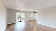 Located at 840 S Grand Hwy in Clermont, FL, this one-bedroom, two-bathroom unit offers a thoughtfully arranged single-floor layout. The open living room is a bright, welcoming space featuring warm wood-look flooring, a ceiling fan, and a textured ceiling. A sliding glass door floods the room with natural light and provides direct access to a private balcony with outdoor views, making the living area feel especially airy and connected to the surroundings. Neutral gray walls throughout create a clean, modern palette.

The galley-style kitchen is efficiently designed with white cabinetry lining both walls, light countertops, a double sink, and white appliances including a range and refrigerator. A window brings in additional natural light, enhancing the kitchen's functional appeal.

The generously sized bedroom continues the wood-look flooring and neutral tones, offering a calm and comfortable retreat. It is complemented by a walk-in closet with a full-width hanging rod, providing ample storage. The two bathrooms are finished in crisp white, each featuring a vanity with white cabinetry, a mirror, and a shower-tub combination. A hallway connects the private areas of the unit, completing this well-organized and practical floor plan.