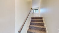Located at 3205 Fairfax St in Eau Claire, Wisconsin, this modern multi-level home offers a thoughtfully designed layout across three floors. The ground level features an attached two-car garage with automatic opener, providing convenient and secure parking. The main living floor hosts an open-concept kitchen and living area finished with light hardwood-style flooring. The kitchen stands out with crisp white shaker cabinetry, a textured geometric tile backsplash, white quartz countertops, stainless steel appliances including a dishwasher, and a large black-framed window that fills the space with natural light and views of the surrounding greenery. A half bathroom with wood-look tile flooring and a pedestal sink completes this level. The upper floor is home to two generously sized bedrooms, each carpeted and bathed in natural light from modern black-framed windows offering views of the tree-lined surroundings. The primary bedroom connects to a spacious walk-in closet with multi-level wire shelving and its own en-suite bathroom. A second full bathroom serves the remaining bedroom. Ambient LED cove lighting accents the upper-level living areas, adding a sleek, contemporary touch. The property is set on a lush, tree-filled lot, providing a peaceful natural backdrop.