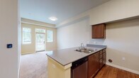 This single-floor residence at 10420 NE 51st Cir in Vancouver, WA offers a thoughtfully designed open layout that connects the kitchen and living areas seamlessly. The kitchen is well-appointed with rich medium-toned wood cabinetry, gray laminate countertops, and a full suite of stainless steel appliances, including a refrigerator, range, and built-in microwave. A peninsula with a double-basin sink and integrated dishwasher extends into the living area, providing both additional prep space and a natural transition between the two zones. The living area features plush carpeting and is brightened by a sliding glass patio door that invites natural light and provides outdoor access. The vaulted ceiling in the living space adds a sense of openness and volume. Bedrooms are carpeted and include walk-in closet storage with built-in shelving. The bathrooms are finished with wood-grain vinyl flooring, warm-toned vanities, and well-lit mirrors. The primary bathroom includes accessibility grab bars and a tub/shower combination, while a secondary half-bath offers a compact vanity and toilet. Throughout, the warm neutral palette and wood-tone finishes create a cohesive, welcoming ambiance.
