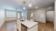 This single-floor residence at 2470 Cherry Laurel Dr in Sanford, Florida presents a clean, contemporary design throughout. The kitchen serves as a central highlight, featuring a large island with a quartz countertop, undermount sink, and pendant lighting overhead. White shaker cabinetry extends to the ceiling, complemented by a tile backsplash and a full suite of stainless steel appliances, including a refrigerator, range, microwave, and dishwasher. Wood-look flooring runs through the main living areas, adding warmth to the bright, neutral palette.

The bedrooms are carpeted and include ceiling fans, with windows fitted with blinds that allow for natural light control. The primary suite connects to a spacious walk-in closet with wire shelving and leads to a private bathroom featuring marble-style tile flooring, a glass-enclosed shower, a long vanity with ample cabinet storage, and a large mirror. A secondary bathroom offers a tub-shower combo with matching marble-style tile and a single-sink vanity. A dedicated laundry room houses a full-size washer and dryer alongside a water heater, providing added convenience within the unit.