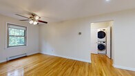 Located at 824 Mountain Ave in Westfield, NJ, this single-floor 2-bedroom, 1-bathroom residence offers a clean, functional layout with consistent hardwood flooring throughout the main living areas. The living space is bright and open, featuring warm honey-toned hardwood floors, a ceiling fan with light fixture, and clean white walls that create a neutral, welcoming ambiance. A convenient in-unit stacked washer and dryer is accessible directly from the living area. The kitchen is well-equipped with warm wood cabinetry, dark granite countertops, stainless steel appliances including a range and over-the-range microwave, and light tile flooring. A large window in the kitchen frames a lush, green outdoor view, filling the space with natural light. The spacious primary bedroom features gleaming hardwood floors, recessed lighting, and a wide window with a radiator beneath it, allowing for comfortable year-round living. The second bedroom includes a built-in closet with shelving, offering ample storage. The bathroom is finished with large-format neutral tile surrounding a soaking tub and shower, complemented by a white vanity and a frosted window for privacy and light. A connecting hallway ties the rooms together seamlessly.