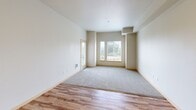 Located at 3900 Veterans Drive in Kent, Washington, this two-bedroom, one-bathroom unit offers a practical and well-designed layout across a single floor. The open-concept living and kitchen area serves as the heart of the home, featuring warm wood-style flooring and recessed lighting that create a bright, welcoming atmosphere. The kitchen is equipped with dark espresso cabinetry, gray laminate countertops, a stainless steel sink, and a full suite of stainless steel appliances including a refrigerator, range, and microwave. A peninsula counter separates the kitchen from the living area, providing additional prep space and a natural flow between the two zones.

Both bedrooms are carpeted and bathed in natural light through large windows fitted with blinds, offering views of the surrounding greenery and landscape. The primary bedroom is generously proportioned, featuring multiple windows and a closet with wire shelving for organized storage. The second bedroom is cozy and functional, also with a window and baseboard heating. The full bathroom includes a tub-shower combination with clean white surround and tile flooring. Throughout the unit, neutral tones and clean lines contribute to a calm, move-in ready aesthetic.