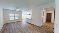This contemporary single-floor unit offers a thoughtfully designed open-concept layout that seamlessly connects the living area and kitchen. Rich hardwood-style flooring flows throughout, providing a warm and cohesive aesthetic across the space. The living area is generously proportioned, bathed in natural light from multiple windows fitted with blinds, and accented by a ceiling fan overhead.

The kitchen is a standout feature, showcasing sleek gray cabinetry with matte black hardware, striking granite countertops, and stainless steel appliances. A peninsula with pendant lighting serves as both a functional workspace and a stylish visual divider between the kitchen and living areas.

The bedrooms offer comfortable, well-lit retreats, each with hardwood-style flooring, ceiling fans, and windows that allow natural light to filter in. The bathroom is cleanly finished with consistent flooring and granite-topped vanity cabinetry, complemented by practical storage solutions nearby.

A dedicated in-unit laundry area provides added convenience with washer and dryer hookups and built-in shelving. Throughout the unit, clean white walls, wide baseboards, and consistent modern finishes create a bright, cohesive ambiance that is both functional and inviting.