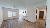 This contemporary single-floor unit offers a thoughtfully designed open-concept layout that seamlessly connects the living area and kitchen. Rich hardwood-style flooring flows throughout, providing a warm and cohesive aesthetic across the space. The living area is generously proportioned, bathed in natural light from multiple windows fitted with blinds, and accented by a ceiling fan overhead.

The kitchen is a standout feature, showcasing sleek gray cabinetry with matte black hardware, striking granite countertops, and stainless steel appliances. A peninsula with pendant lighting serves as both a functional workspace and a stylish visual divider between the kitchen and living areas.

The bedrooms offer comfortable, well-lit retreats, each with hardwood-style flooring, ceiling fans, and windows that allow natural light to filter in. The bathroom is cleanly finished with consistent flooring and granite-topped vanity cabinetry, complemented by practical storage solutions nearby.

A dedicated in-unit laundry area provides added convenience with washer and dryer hookups and built-in shelving. Throughout the unit, clean white walls, wide baseboards, and consistent modern finishes create a bright, cohesive ambiance that is both functional and inviting.