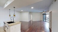 Located on Hollyhurst Lane in Houston's 77056 corridor, this well-appointed two-bedroom, two-bathroom residence offers a thoughtfully designed single-floor layout. The open-concept kitchen and living area serves as the heart of the home, featuring rich hardwood flooring, a curved granite-topped island with a matte black undermount sink, stainless steel appliances, crisp white shaker cabinetry, a subway tile backsplash, and striking pendant lights with gold accents that add a modern flair. The living room is generously proportioned, illuminated by a ceiling fan and bathed in a neutral palette that creates a bright, airy ambiance. Both bedrooms are finished with plush wall-to-wall carpet and windows offering views of the surrounding urban landscape. The primary bedroom connects to a dedicated walk-in closet equipped with wire shelving and ample storage capacity. The bathrooms are finished with tile flooring, granite vanity countertops, white cabinetry, and a tiled tub-shower combination. A private balcony with metal railing extends the living space outdoors, offering a glimpse of the community pool below. A hallway connects all rooms seamlessly, completing this clean and functional Houston residence.