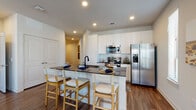 This thoughtfully designed single-floor residence combines contemporary finishes with a warm, functional layout. The open-concept kitchen serves as a central hub, showcasing white shaker cabinetry, a classic subway tile backsplash, dark granite countertops, and a full suite of stainless steel appliances including a side-by-side refrigerator, range, and over-the-range microwave. A peninsula island with seating for three provides an ideal space for casual dining or entertaining. Rich wood-style flooring flows throughout the main living areas, creating a cohesive and inviting atmosphere. The dining area benefits from large windows dressed with sheer curtains, filling the space with natural light. The living room offers a relaxed, open feel with ceiling fan, generous window coverage, and direct access to an outdoor patio through French doors. The bedrooms are carpeted for comfort, each featuring ceiling fans and windows that bring in natural light. The primary bathroom is notably spacious, with an extended vanity topped in dark granite, ample cabinetry, and a walk-in closet, while a second bathroom mirrors the same refined finishes. Recessed lighting throughout adds a polished, modern touch to every room.
