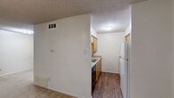 Located at 200 Hann Street in Denton, TX, this single-floor unit offers a practical and efficient layout encompassing one bedroom, one bathroom, a kitchen, and a closet. The generously sized bedroom features neutral-toned carpet flooring, crisp white walls, and a textured ceiling, creating a clean and simple living environment. A ceiling fan with a light fixture provides both comfort and illumination, while a window allows natural light to fill the space. An open closet with a hanging rod sits conveniently adjacent, offering dedicated storage. The kitchen is outfitted with warm wood-toned cabinetry, ample counter space on both sides, and durable wood-look flooring, providing a functional cooking area with good storage capacity. The bathroom includes a full-size soaking tub and shower combination with clean white surrounds, a toilet, and a sink, maintaining a straightforward and tidy design. The textured ceilings are consistent throughout the unit. The overall layout, as seen in the dollhouse view, is compact yet well-organized, making efficient use of every square foot available.