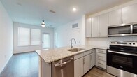 Located in the heart of Tampa's Hyde Park area, this single-floor residence at 510 N Rome Ave offers a thoughtfully designed layout with modern finishes throughout. The open-concept kitchen serves as the centerpiece of the living area, featuring granite countertops, a large peninsula with an undermount sink, gray shaker-style cabinetry, a classic subway tile backsplash, and a full suite of stainless steel appliances including a refrigerator, electric range, microwave, and dishwasher. Wood-look flooring runs through the main living and kitchen areas, adding warmth and continuity to the space. The bedrooms are generously sized, each with plush carpeting, ceiling fans, and windows with blinds that allow for natural light. The primary bathroom includes a granite-topped vanity, wood-look flooring, and direct access to a walk-in closet. A secondary full bathroom offers a clean, white tiled tub-shower combination, a matching granite vanity, and wood-look flooring. Recessed lighting and ceiling fans throughout contribute to a bright, comfortable ambiance, while the clean, neutral color palette provides a versatile backdrop suited to a variety of interior styles.