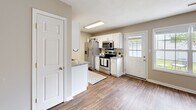 This two-story residence at 7504 1 offers a thoughtfully designed layout spread across two levels, connected by a staircase visible in the floor plan. Warm hardwood-style flooring flows consistently throughout the home, creating a cohesive and inviting aesthetic.

The kitchen is well-equipped, featuring white cabinetry, granite countertops, a stainless steel appliance suite including a refrigerator, range, microwave, and dishwasher, along with a peninsula that provides additional counter space. Natural light enters through a window near the back door entry.

The upper level includes a vaulted bedroom with angled ceilings and a ceiling fan, adding architectural character to the space. A second flexible room on this level serves well as a home office, complete with a ceiling fan and a window overlooking the exterior. Both levels include bathrooms featuring hardwood-style flooring, tub-shower combinations, and vanities with granite countertops.

Additional bedrooms with ceiling fans and en-suite access provide comfortable and functional living spaces. Neutral warm-toned walls throughout the home complement the flooring and create a bright, welcoming atmosphere.