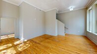 Located at 1601 Main St in the heart of Columbia, SC, this one-bedroom, one-bathroom residence offers a well-designed layout across a single floor. The living area is immediately welcoming, featuring warm, honey-toned hardwood floors that run throughout and a textured ceiling that adds character to the space. A staircase is prominently positioned in the main living area, serving as a functional architectural element. Large, tall windows flood the living room with generous natural light, framing views of the tree-lined streetscape outside.

The hallway connects the living spaces to the private areas of the home, leading to the bedroom, which benefits from its own oversized window with street-facing views, continuing the natural light theme. A dedicated walk-in closet accompanies the bedroom, outfitted with wire shelving and hanging rods to maximize storage. The bathroom is clean and modern, featuring large-format gray tile flooring, a dark espresso vanity with a granite-topped sink, a well-lit mirror, and a bathtub/shower combination. Neutral wall tones throughout the residence create a cohesive and versatile backdrop suited to a variety of interior styles.