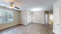 Located at 1300 Lakeridge Rd in Hampton, Virginia, this single-floor unit offers a well-organized layout designed for comfortable everyday living. The main living area features wood-style flooring throughout and is brightened by natural light from multiple windows with blinds, complemented by a ceiling fan overhead. Adjacent to the living space, a defined dining area is highlighted by an elegant chandelier and a chair-rail accent along the neutral-toned walls, creating a polished, transitional feel between spaces.

The kitchen is outfitted with white cabinetry, granite-style countertops, and a full suite of stainless steel appliances, including a refrigerator, range, microwave, and dishwasher. A dedicated utility room directly off the kitchen houses an in-unit washer and water heater, adding functional convenience.

The bedrooms feature plush carpeting and include closets with built-in hanging rods and shelving. At least one bedroom connects directly to a bathroom featuring a vanity with white cabinetry and a large mirror. An additional bathroom with similar finishes serves the remaining rooms. Throughout the unit, neutral wall tones, textured ceilings, and consistent trim details contribute to a clean, cohesive aesthetic.