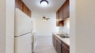 Located at 956 12th St SW in Forest Lake, Minnesota, this two-bedroom, one-bathroom residence offers a practical and well-organized single-floor layout. The galley-style kitchen is outfitted with rich, dark wood cabinetry — both upper and lower — paired with a double-basin sink, white appliances including a range and refrigerator, and light vinyl plank flooring. A ceiling fan overhead adds comfort to the space, which opens toward the living area. The living room is bright and inviting, featuring large sliding glass doors that lead to a balcony with views of surrounding trees, allowing abundant natural light to fill the room. Baseboard heating runs along the walls, and light vinyl plank flooring continues throughout the main living areas. Both bedrooms are carpeted and well-sized, each with ceiling fans and windows that bring in natural light and outdoor views. The primary bedroom includes a generous walk-in closet with dual hanging rods and built-in shelving. The full bathroom features white tile surrounding the tub-shower combination, a mosaic tile floor, and clean, classic fixtures. A hallway connects the main living areas to the bedrooms, with additional closet storage available. This home offers a comfortable and functional layout suited for everyday living.