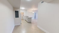 Located at 14981 SW 283 St in Homestead, FL, this single-story unit offers a clean, modern layout designed for comfortable living. The open-concept kitchen serves as the centerpiece of the main living area, featuring a peninsula with granite countertop and an integrated sink, light gray cabinetry, white appliances including a refrigerator, electric range, and microwave, and a walk-in pantry closet. A pendant light fixture above the peninsula adds a refined touch to the space.

The kitchen flows seamlessly into the living and dining areas, which are bathed in natural light from sliding glass doors fitted with vertical blinds. Light-toned large-format tile flooring extends throughout, creating a cohesive and airy feel. The living area provides direct outdoor access, enhancing the connection to natural light and ventilation.

The bedrooms are well-proportioned, each with the same light tile flooring and ample wall space. The electrical panel is conveniently integrated near the entry. The bathrooms are finished with granite-topped vanities, white cabinetry, large mirrors, and tub-shower combinations with tile surrounds. Clean white walls and recessed lighting throughout contribute to a bright, neutral palette that defines this well-appointed Homestead residence.