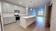 This contemporary 860 square foot apartment in Bel Air, Maryland, offers a thoughtful blend of style and functionality. The open-concept design seamlessly integrates the kitchen, living, and dining areas, creating a spacious feel. The kitchen is a standout feature, boasting white cabinetry, stainless steel appliances, and a central island with pendant lighting, perfect for casual dining or food preparation.

The bedroom, measuring 170 square feet, provides ample space and features plush carpeting and a ceiling fan for comfort. Large windows allow natural light to flood the room, while an adjoining walk-in closet offers generous storage. The bathroom continues the modern aesthetic with a sleek vanity, large mirror, and a shower/tub combination with sliding glass doors.

Practical amenities include an in-unit laundry room with full-sized washer and dryer, and additional storage solutions. The apartment's flooring alternates between warm wood-look planks in main living areas and soft carpeting in the bedroom, adding to the overall comfort and style. Recessed lighting throughout ensures a bright, welcoming atmosphere at any time of day.