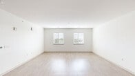 This single-floor unit offers a clean, contemporary design characterized by a neutral color palette, crisp white walls, and an abundance of natural light throughout. The spacious main living area features light-toned hardwood-style flooring that reflects natural light from two large windows fitted with horizontal blinds, creating an open and airy atmosphere.

The kitchen is thoughtfully designed with light wood flat-panel cabinetry, light quartz countertops, a white subway tile backsplash, and a full suite of stainless steel appliances including a refrigerator, range, microwave, and dishwasher. Open shelving adds a modern touch to the kitchen's functional layout.

The bedrooms are finished with plush carpet flooring and feature windows with outdoor views. At least one bedroom includes a walk-in closet with built-in shelving, providing generous storage. Additional interior doors offer well-organized access to closets and utility areas.

The bathroom is elegantly appointed with warm wood-toned vanity cabinetry, a white quartz countertop, an undermount sink, and gold-accented wall sconces flanking a large mirror. A full soaking tub with a tiled surround and light hardwood-style flooring complete the space. Throughout the unit, black hardware accents lend a cohesive, modern aesthetic.