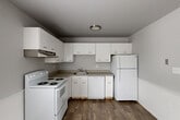 Located at 2716 Packard St in Ann Arbor, MI, this 2-bedroom, 1-bathroom unit offers a practical and well-organized single-floor layout. The living room features neutral carpet flooring, clean white walls, and a window with natural light, opening into a connected dining area that provides a seamless flow between spaces. The kitchen is efficiently designed in a U-shaped configuration, outfitted with white cabinetry, ample upper and lower storage, a range, dishwasher, and refrigerator, all set above wood-look vinyl flooring. A second room with wood-look flooring, wainscoting, and a ceiling fan serves as a versatile dining or secondary living space with natural light from a large window. Both bedrooms are carpeted and feature windows with blinds, baseboard heating, and wall-unit air conditioning. The primary bedroom includes a mirrored sliding closet door, while the layout also includes multiple additional closets for storage. The bathroom is finished with a gray vanity featuring a white countertop, wood-look tile flooring, a window for natural light, and a full bathtub with shower. Hallways connect the rooms efficiently, contributing to the unit's cohesive and functional design throughout.