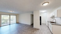This single-floor, 2-bedroom, 1-bathroom residence offers a functional and thoughtfully designed layout. The open-concept living and dining area features light gray wood-style flooring, a textured ceiling, and a sliding glass door that invites natural light and outdoor views. The galley-style kitchen has been tastefully updated with crisp white shaker cabinetry, classic subway tile backsplash, dark countertops, a stainless steel sink, and a full suite of stainless steel appliances including a refrigerator, electric range, microwave, and dishwasher. In-unit laundry is also conveniently located just off the kitchen. The primary bedroom is generously sized, complete with a wide built-in closet and plush carpeting, while a hallway leads to a dedicated walk-in closet with dual wire shelving systems for ample storage. The second bedroom features carpeted flooring and a window with natural views. The shared bathroom includes a full tub-shower combo finished with clean white subway tile and brushed nickel fixtures. Throughout the residence, neutral tones and consistent finishes create a cohesive, move-in-ready atmosphere.
