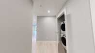 This thoughtfully designed single-floor unit offers three bedrooms and two bathrooms within a efficiently arranged, modern floor plan. The interior is finished with light-toned luxury vinyl plank flooring and soft grey walls throughout, creating a clean, cohesive aesthetic.

The kitchen is a standout feature, boasting high-gloss white cabinetry, quartz countertops, stainless steel appliances including a range and refrigerator, recessed lighting, and a central island with an integrated sink — ideal for both cooking and entertaining.

The living area is bright and airy, with large sliding glass doors opening onto a private balcony that overlooks lush greenery, allowing abundant natural light to fill the space.

The bedrooms are well-proportioned, each featuring large windows with garden and neighbourhood views, baseboard heating, and light-filled interiors. One bedroom includes a wall-mounted mini-split air conditioning unit for added comfort, while another features a sliding closet for convenient storage.

The two bathrooms are finished in a clean, modern style. One includes a full soaker tub-shower combo with chrome fixtures, while the other features a glass-enclosed standing shower — both with white vanities and quartz countertops.

A dedicated in-suite laundry closet with a stacked washer and dryer adds practicality, and a hallway connects all rooms seamlessly for an efficient and functional layout.