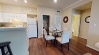 This thoughtfully designed single-floor residence offers a warm and inviting atmosphere throughout, highlighted by rich hardwood flooring and neutral tones that create a cohesive and elegant aesthetic. The entryway greets visitors with crown molding details and direct access to a convenient closet, setting the tone for the well-finished interiors beyond.

The kitchen features white cabinetry, recessed lighting, and a peninsula with bar seating for two, making it an ideal space for casual dining and entertaining. It flows seamlessly into the dining area, where a glass-top table and tufted upholstered chairs are positioned beside a built-in shelving nook perfect for a pantry or wine storage, adding both function and character.

The living room is a bright and comfortable retreat, benefiting from natural light through a large window. Crown molding, vaulted ceiling accents, and plush neutral seating contribute to its relaxed yet refined feel.

A secondary bedroom offers carpeted flooring, a window with outdoor views, and ample space for flexible use. The full bathroom is clean and functional, featuring a single-sink vanity with generous counter space, a tub-shower combination, and hardwood flooring. Every area of this home reflects careful attention to comfort and practical design.