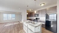 Located at 4584 Samoyed Dr. in Columbus, Ohio, this single-floor home offers a well-designed, open layout that balances functionality with comfort. Wood-look flooring flows throughout the main living areas, while neutral-toned walls create a bright, welcoming atmosphere throughout.

The kitchen serves as a central hub of the home, featuring rich dark cabinetry, stone-look countertops, a center island with a built-in sink, and pendant lighting overhead. Black appliances — including a refrigerator, electric range, and microwave — are seamlessly integrated. The kitchen opens directly into the living area, which is bathed in natural light from a wide bank of windows and provides access to an exterior door leading to an outdoor space.

The bedrooms are carpeted for warmth and comfort, each offering windows that allow natural light to fill the rooms. A spacious walk-in closet with wire shelving provides generous storage. The bathroom is appointed with a dual-sink vanity, dark cabinetry, stone-look countertops, and elegant vanity lighting above a large mirror.

A hallway with textured ceilings and additional closet space connects the rooms, completing this thoughtfully arranged single-level home ideal for everyday living.