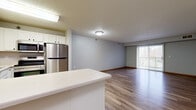 Located at 1321 Lake Dr W in Chanhassen, MN, this 2-bedroom, 2-bathroom residence offers a well-designed, single-floor layout that balances comfort and functionality. The open-concept kitchen and living area forms the heart of the home, featuring white cabinetry, stainless steel appliances including a refrigerator, stove, and microwave, a white peninsula countertop ideal for casual dining, and wood-look luxury vinyl plank flooring that flows seamlessly into the living room. A sliding glass door in the living area provides natural light and access to a private balcony. Both bedrooms are carpeted and feature windows that allow for ample natural light, with the primary bedroom offering a ceiling fan and a generously sized walk-in closet equipped with wire shelving for organized storage. The two bathrooms are finished with light tile flooring, white vanities with countertops, and clean, neutral tones. A dedicated in-unit laundry room houses a full-sized washer and dryer alongside wire shelving for additional storage. Throughout the residence, wood baseboards, textured ceilings, and a neutral color palette create a cohesive and practical living environment.