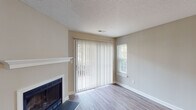 Located at 813 Stadium Dr in Wake Forest, NC, this single-floor home offers a thoughtfully designed layout with a clean, neutral aesthetic throughout. The living area serves as a welcoming focal point, anchored by a classic fireplace with a white mantel and flanked by a sliding glass door with vertical blinds and a side window, allowing natural light to fill the space. Light-toned hardwood-style flooring runs throughout, tying each room together cohesively.

The kitchen is well-equipped and modern, featuring white shaker-style cabinetry, dark granite countertops, a peninsula with an undermount sink, and a full suite of stainless steel appliances including a refrigerator, electric range, and built-in microwave. A tile backsplash adds a polished finishing touch, while track lighting illuminates the workspace effectively.

The bedroom is generously proportioned, offering two windows with exterior views, a ceiling fan with integrated light fixture, and access to a roomy closet with a full-width hanging rod. An adjacent bathroom is accessible directly from the bedroom and features a full soaking tub with a handheld showerhead and clean white surround. The textured ceilings and crisp white trim throughout lend the home a tidy, well-maintained character.