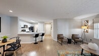 This well-appointed 2-bedroom, 2-bathroom residence in Tucker, Georgia offers a thoughtfully designed single-floor layout that maximizes comfort and functionality. The open-concept living, dining, and kitchen area serves as the heart of the home, bathed in natural light from large windows and a glass patio door. The kitchen is a standout feature, showcasing white shaker-style upper cabinets, contrasting gray lower cabinets, light stone countertops, a peninsula with bar seating, a black matte faucet, and black appliances including a refrigerator, range, and microwave. The living area flows seamlessly to a private patio, enhancing the indoor-outdoor connection. Light wood-look flooring runs throughout, complementing the neutral gray wall tones and textured ceilings. The spacious primary bedroom features a ceiling fan, natural light from a large window, and generous closet space. The second bedroom is equally well-lit with its own ceiling fan and window views. Both bathrooms are clean and functional, with one offering a tub-shower combo and updated vanity. An in-unit laundry area with washer hookups, abundant storage across eight closets with wire shelving, and a dedicated patio round out this practical and comfortable home.