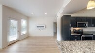 This single-story residence at 30 Ayla Dr in Little Rock, Arkansas presents a clean, modern aesthetic defined by a neutral palette, light hardwood flooring, and thoughtfully designed living spaces. The open-concept living area is bright and airy, benefiting from multiple windows that draw in natural light. A sleek wall-mounted fireplace serves as a focal point, complementing the minimalist design.

The kitchen is a standout feature, showcasing bold navy shaker-style cabinetry paired with speckled granite countertops and a generous central island ideal for meal preparation or casual dining. Stainless steel appliances, including a range, microwave, refrigerator, and dishwasher, complete the space. Pendant lighting and a skylight add warmth and visibility.

The bedrooms are well-proportioned, each featuring light hardwood floors, ceiling fans, and natural light from exterior windows. Closet space is integrated thoughtfully. The bathroom includes a walk-in tile shower with a glass enclosure, recessed niche shelving, and sleek dark cabinetry for storage. Throughout the home, recessed lighting, clean white walls, and consistent flooring create a cohesive, move-in-ready environment.