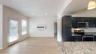 This single-story residence at 30 Ayla Dr in Little Rock, Arkansas presents a clean, modern aesthetic defined by a neutral palette, light hardwood flooring, and thoughtfully designed living spaces. The open-concept living area is bright and airy, benefiting from multiple windows that draw in natural light. A sleek wall-mounted fireplace serves as a focal point, complementing the minimalist design.

The kitchen is a standout feature, showcasing bold navy shaker-style cabinetry paired with speckled granite countertops and a generous central island ideal for meal preparation or casual dining. Stainless steel appliances, including a range, microwave, refrigerator, and dishwasher, complete the space. Pendant lighting and a skylight add warmth and visibility.

The bedrooms are well-proportioned, each featuring light hardwood floors, ceiling fans, and natural light from exterior windows. Closet space is integrated thoughtfully. The bathroom includes a walk-in tile shower with a glass enclosure, recessed niche shelving, and sleek dark cabinetry for storage. Throughout the home, recessed lighting, clean white walls, and consistent flooring create a cohesive, move-in-ready environment.