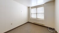 This 510 square foot apartment, located at 612 South St in Utica, NY, offers a well-designed living space on a single floor. The layout comprises one bedroom, one bathroom, and a kitchen, efficiently utilizing the available area. The primary bedroom, measuring 120 square feet, provides ample space for essential furnishings.

The bathroom features a clean, modern design with a white vanity, mirror with overhead lighting, standard toilet, and a shower/tub combination. Beige tile flooring complements the overall neutral color scheme. The kitchen, though compact, is functional with wooden cabinetry, white appliances, and a double sink. A pass-through counter adds a touch of openness to the space.

The bedroom, while modest in size, benefits from natural light through a large window with horizontal blinds. Neutral walls and carpeting create a blank canvas for personalization. The apartment's common areas feature the same neutral tones and carpeting, promoting a sense of continuity throughout the space.

Storage solutions are integrated into the design, with built-in closets visible in the hallway. The overall ambiance is clean, bright, and practical, making efficient use of the limited square footage to create a comfortable living environment.