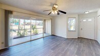 Located at 3099 Park Village Way in Melbourne, Florida, this well-organized 2-bedroom, 3-bathroom residence offers a functional and comfortable single-floor layout. The open-concept living, dining, and kitchen area serves as the heart of the home, featuring hardwood-style flooring, a ceiling fan with light fixture, and a textured ceiling. Large sliding glass doors flood the living room with natural light and provide direct access to a private balcony with outdoor views of lush tropical greenery. The kitchen is designed as a galley-style space equipped with ample cabinetry, a range, dishwasher, and a pass-through that opens to the main living area. A pendant light fixture accents the adjacent dining area. The primary bedroom offers generous proportions, a ceiling fan, a walk-in closet with wire shelving systems, and large sliding glass doors that bring in additional natural light. The second bedroom also features a ceiling fan and a bright window with outdoor views. Three full bathrooms include wide vanities, large mirrors, and tiled tub-shower combinations. Additional highlights include four closets, a dedicated pantry, a laundry area, a utility room, and a hallway connecting all spaces efficiently.