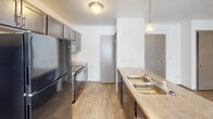 Located at 418 Hein Ave in Sioux Falls, South Dakota, this single-floor residence offers a well-organized and functional layout designed for comfortable everyday living. The kitchen is a standout space, featuring dark cabinetry, a double-basin sink, hard surface flooring, pendant lighting, and a full suite of black appliances including a refrigerator, range, and over-the-range microwave. The open flow from the kitchen connects naturally to the rest of the home. The living area is generously sized, finished with plush carpeting, a ceiling fan with light fixture, and a large sliding glass door fitted with vertical blinds that allows for abundant natural light. Multiple bedrooms continue the warm, carpeted aesthetic, each offering windows with blinds for natural light and privacy, along with closet access and ceiling-mounted light fixtures. The bathrooms are clean and efficiently designed, each equipped with a full tub and shower combination featuring chrome fixtures. A dedicated in-unit laundry area houses a full-size side-by-side washer and dryer, complemented by an overhead shelf for additional storage. Throughout the space, neutral white walls and light-toned finishes create a bright, clean, and move-in-ready atmosphere.
