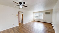 Located at 5400 Hamilton Ave in Cincinnati, Ohio, this single-floor, two-bedroom, one-bathroom unit offers a practical and comfortable layout. Warm hardwood flooring flows consistently throughout the living spaces, creating a cohesive and inviting atmosphere.

The living room is generously proportioned, featuring white walls, a ceiling fan, and baseboard heating. A narrow window brings in natural light, and the open feel of the room allows for flexible furniture arrangements.

Both bedrooms continue the hardwood flooring and feature white walls with textured ceilings. The primary bedroom is well-sized and includes a dedicated closet with built-in shelving, offering ample storage. A window provides natural light and ventilation, complemented by a wall-mounted air conditioning unit and baseboard heating. The second bedroom also offers comfortable proportions, a natural wood interior door, and easy access to the rest of the unit.

The bathroom is finished with classic white tile, featuring a full-size soaking tub with an overhead shower, mosaic tile flooring with decorative accents, and clean, neutral walls. A kitchen with wood cabinetry rounds out the unit's functional offerings. Overall, this space provides a clean, straightforward living environment suited for everyday comfort.