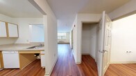 Located at 1040 E 33rd St in Baltimore, MD, this one-bedroom, one-bathroom residence offers a practical and comfortable floor plan across a single level. Rich hardwood-style flooring flows throughout the main living areas, adding warmth and continuity to the space. The open living room is bright and airy, featuring a large window that frames views of surrounding greenery and allows natural light to fill the room. A wall-unit HVAC system ensures year-round comfort. The kitchen is thoughtfully designed with white cabinetry accented by wood-tone trim, white appliances including a refrigerator, electric range, and dishwasher, and a skylight overhead that bathes the space in additional light. A pass-through connects the kitchen to the living area, enhancing the open feel. A convenient closet near the entryway provides additional storage. The bedroom is generously proportioned, featuring plush carpeting, a window with outdoor views, and a wide built-in closet with adjustable shelving for organized storage. The bathroom is clean and functional, appointed with white tile surrounding a tub-shower combination, a pedestal sink, mirrored medicine cabinet, and hardwood-style flooring.