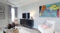 This single-floor residence is thoughtfully designed with a contemporary aesthetic, featuring light hardwood-style flooring and a neutral grey-and-taupe color palette that flows consistently throughout. The living room offers a bright, open feel with tray ceiling detailing, natural light from draped windows, and ample space for comfortable seating arrangements. A secondary sitting room provides an intimate retreat, bathed in natural light from dual windows framed by patterned drapes.

The kitchen is outfitted with dark espresso cabinetry, light stone countertops, stainless steel appliances, and a central island. A sliding glass door opens directly onto a private balcony overlooking a wooded outdoor view, blending indoor and outdoor living seamlessly.

The primary bedroom features a tray ceiling with a ceiling fan, large windows, and direct access to an en-suite bathroom equipped with a dual-sink vanity, dark cabinetry, stone countertops, and a glass-enclosed shower. A second bedroom includes a walk-in closet with built-in organization. A secondary full bathroom offers a white vanity with stone countertops and clean tile flooring, providing practical functionality throughout the residence.