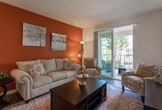 Located at 14951 Foothill Blvd in Fontana, California, this single-story residence offers a well-designed, open-concept floor plan with a warm and inviting aesthetic throughout. The living area serves as the heart of the home, anchored by a striking burnt-orange accent wall that adds depth and character to the space. A sliding glass door fills the room with natural light and provides direct access to a private balcony with outdoor views.

The kitchen is thoughtfully appointed with crisp white shaker cabinetry extending to the ceiling, stainless steel appliances including a French door refrigerator, gas range, built-in microwave, and dishwasher. A central island with seating offers additional prep space and casual dining. The bold orange backsplash ties seamlessly into the home's cohesive color palette, while wood-look flooring runs throughout, adding warmth and continuity.

The bedrooms are comfortably sized, each equipped with ceiling fans and ample closet space. One room features a mirrored sliding closet door, while another offers a dedicated walk-in closet area. The bathrooms are clean and functional, featuring white vanities with ample storage, tub-shower combinations, and wood-look flooring. The overall ambiance of this residence is warm, modern, and move-in ready.
