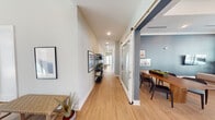 Located at 275–339 Old Gurley Rd NE in Huntsville, Alabama, this single-story community clubhouse offers a thoughtfully designed amenity space for residents. The interior features light hardwood flooring throughout, crisp white trim, and a cohesive color palette of soft grays and deep slate blues that lend the space a polished, contemporary feel.

The expansive main lounge serves as the heart of the facility, boasting soaring ceilings, large floor-to-ceiling windows that flood the room with natural light, and direct access to an outdoor pool area. Multiple seating arrangements — including plush sofas, leather chairs, and accent tables — create distinct zones for relaxation and socializing. Wall-mounted televisions add to the versatility of the space.

A formal dining area adjacent to the lounge features sturdy wood tables, black modern chairs, and decorative grid-pane mirrors that enhance the room's depth and style. The space opens seamlessly into a bright, welcoming corridor lined with curated artwork and decorative shelving, leading to additional amenity rooms.

The business center provides a functional workspace with dedicated desks, ergonomic seating, and oversized windows offering views of the surrounding community. A separate game room houses a full-size ping pong table alongside a bistro-style seating nook, providing a recreational retreat. Together, these spaces form a well-rounded, resident-focused facility.