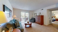 This single-floor, one-bedroom, one-bathroom residence offers a thoughtfully organized layout across a compact yet functional footprint. The living room serves as the heart of the home, featuring light neutral carpet, a textured ceiling, and a full-width sliding glass door with vertical blinds that opens to a private balcony, filling the space with natural light and outdoor views. Adjacent to the living room, the dining area accommodates a full dining table and chairs beneath a decorative ceiling fixture, with a pass-through window connecting it to the kitchen for a convenient, open feel. The galley-style kitchen is equipped with warm wood cabinetry, a tile floor in a neutral stone pattern, a full-size refrigerator, a range, and a double sink with ample counter space on both sides. The generously sized bedroom offers plush carpeting, a ceiling fan with light fixture, and a dedicated closet, providing a restful and private retreat. The full bathroom includes a vanity with wood cabinetry, a tile floor, and a shower-tub combination. A hallway and closet complete the layout, adding practical storage and transitional flow throughout the residence.