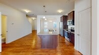 Located at 920 Stockbridge Dr. in Fort Mill, SC, this well-appointed two-story home offers a thoughtfully designed layout across both levels. The main floor showcases warm hardwood flooring throughout, creating a cohesive and inviting atmosphere. The open-concept kitchen is a standout feature, equipped with rich dark wood cabinetry, granite countertops, a center island with a built-in sink and pendant lighting, and a full suite of stainless steel appliances including a refrigerator, range, microwave, and dishwasher. The kitchen flows seamlessly into a bright dining area, highlighted by a classic chandelier and natural light from nearby windows. The expansive living area offers generous open space with direct access to a rear door. A convenient powder room on the main level features a pedestal sink and an octagonal mirror. Upstairs, the home includes a spacious primary suite with hardwood flooring, a private en-suite bathroom featuring a glass-enclosed shower, and a generously sized walk-in closet with wire shelving. A dedicated laundry room houses a full-size washer and dryer with additional overhead shelving for storage. Throughout the home, clean white walls, consistent trim work, and ample natural light contribute to a bright, move-in-ready aesthetic.