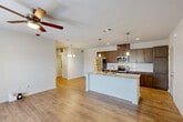 Located at 1931 Chemin Metairie Rd in Youngsville, Louisiana, this well-appointed one-bedroom, one-bathroom unit offers a thoughtfully designed single-level layout. The open-concept living area seamlessly connects the kitchen, dining, and living spaces, all finished with warm wood-tone luxury vinyl plank flooring that extends throughout the main areas. The kitchen serves as the centerpiece, featuring rich dark cabinetry, a large granite-topped island with a double undermount sink, subway tile backsplash, stainless steel appliances including a refrigerator, range, and microwave, and stylish pendant lighting overhead. A ceiling fan in the living area adds comfort, while French doors bring in natural light and provide access to a private patio. The spacious bedroom is carpeted for warmth and comfort, equipped with its own ceiling fan, a natural light-filled window, and access to generous closet space, including a walk-in closet with wire shelving. The full bathroom features granite countertops, dark wood cabinetry, wood-look flooring, and a tub-shower combination. A dedicated in-unit laundry room accommodates full-size washer and dryer units. Three closets throughout the unit provide exceptional storage for a space of this scale.