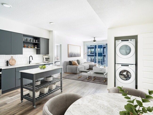 A bright, open layout featuring a dark-cabinet kitchen, movable island, and in-home washer and dryer, creating everyday ease at Modera Encore in Tampa. - Modera Encore