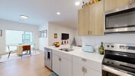 Located at 399 S. Crouse Ave in Syracuse, NY, this modern single-floor residence offers three bedrooms and three bathrooms with a clean, contemporary design throughout. Light wood flooring flows seamlessly across the entire unit, creating a warm and cohesive aesthetic.

The open-concept kitchen and living area serves as the heart of the home. The kitchen features two-tone cabinetry — crisp white lower cabinets paired with natural wood upper cabinets — along with white quartz countertops, stainless steel appliances including a refrigerator, electric range, and built-in microwave, and a peninsula with an undermount sink that opens to the living space. The living room is bright and comfortable, with recessed lighting and a wall-mounted TV.

A clean, well-lit hallway connects the three bedrooms, each of which benefits from natural light provided by large windows. The primary bedroom is a well-proportioned retreat with ample room for furnishings. The additional bedrooms are similarly bright and functional. Each of the three bathrooms features a clean, minimal design with shower enclosures and light, neutral finishes.

The entry foyer includes a coat hook wall and a smart lock entry door, adding a practical and modern touch to the welcoming entryway. Overall, the space presents a bright, well-designed layout with modern finishes throughout.