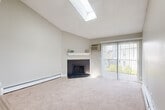 Located in Lakewood, Colorado, this one-bedroom, one-bathroom residence offers a well-designed single-floor layout with a thoughtful mix of comfort and style. The living room is the standout centerpiece of the home, boasting dramatic vaulted ceilings that soar above a skylight, flooding the space with natural light. A dark tile-surround fireplace with a white mantel anchors the room, while a sliding glass door opens to outdoor views and brings in additional sunlight. Plush carpeting runs throughout the living and bedroom areas, complementing the warm, neutral color palette. The galley-style kitchen is efficiently designed with white shaker cabinetry, granite-look countertops, a subway tile backsplash, stainless steel appliances, and light wood-look flooring. A pass-through connects the kitchen to the living area, enhancing the open feel. The bedroom offers a comfortable, well-proportioned layout with a large window overlooking greenery and a textured ceiling. The bathroom features a white vanity with a granite-look countertop, wood-look flooring, and a full tub-shower combination. A hallway and dedicated closet complete the functional floor plan of this Lakewood residence.